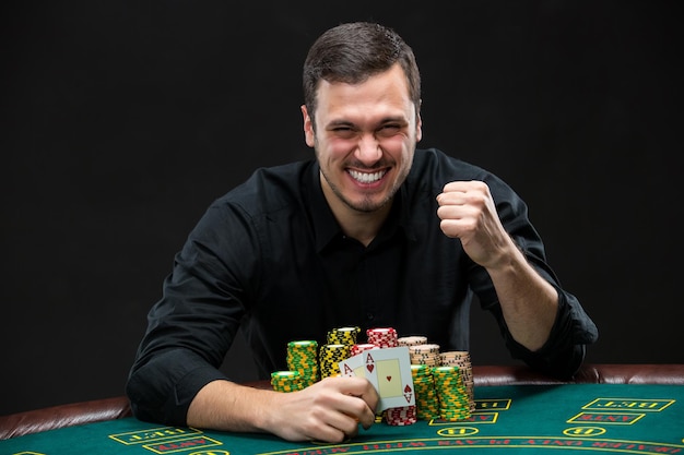 Happy poker player winning and holding a pair of aces