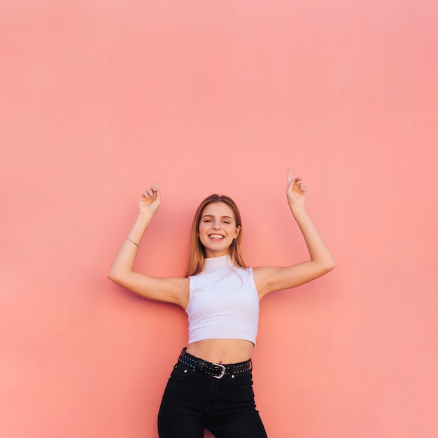 Photo happy portrait of a beautiful young woman raising her arms pointing fingers upward