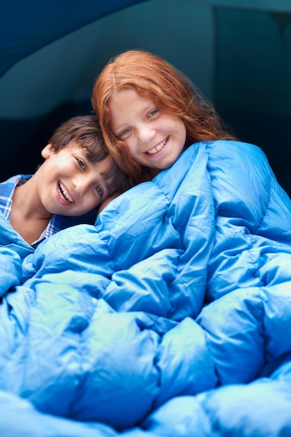 Happy portrait and children hug with blanket for camping comfort and bonding outdoor together Family love and face of kids outside for journey fun or adventure in a forest for vacation sleepover