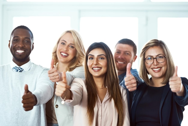 Foto ritratto felice e gruppo di uomini d'affari con il pollice in alto sul posto di lavoro in ufficio gesto della mano del viso e lavoro di squadra dei dipendenti con emoji simili per il successo ok o approvazione dell'accordo e segno di ringraziamento