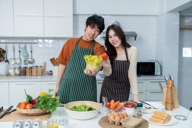 Happy portrait of loving young loving couple asian of having fun standing a cheerful preparing food