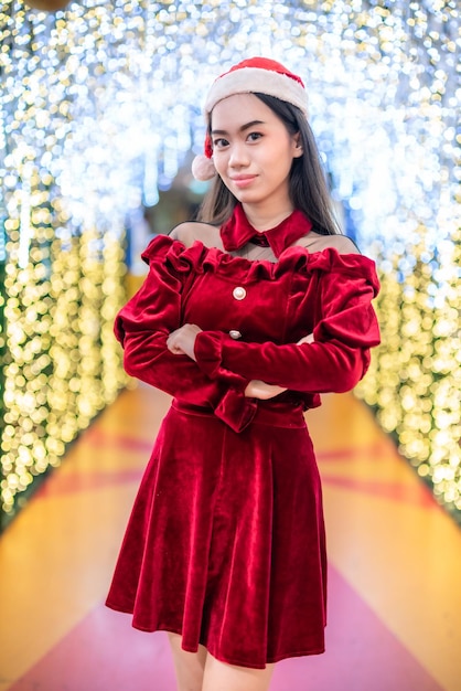 Happy portrait young asian woman santa costume and christmas greeting picture parcel decoration on christmas tree light abstract circular bokeh background decoration during christmas and new year