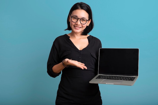 Happy Portret lachende jonge Aziatische vrouw met laptop geïsoleerd op gele achtergrond Mooie Aziatische vrouwelijke bedrijf notebook computer
