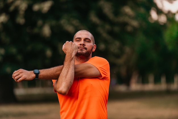 Happy positive sportsman during outdoor workout man wearing\
sports outfit warming up musclesenjoying active lifestyle outside\
in park