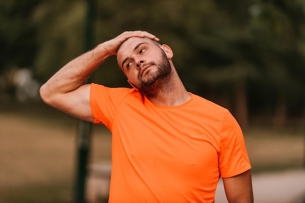 야외 운동 중 행복한 긍정적인 스포츠맨은 운동복을 입고 공원 밖에서 활동적인 생활 방식을 즐기는 근육을 워밍업합니다.