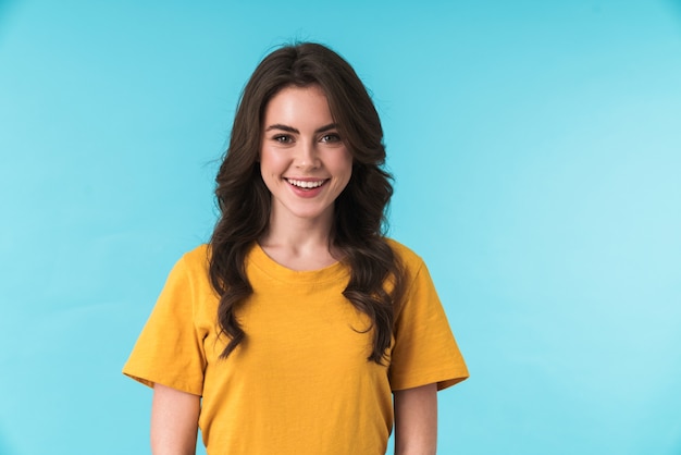 A happy positive young pretty woman posing isolated over blue wall