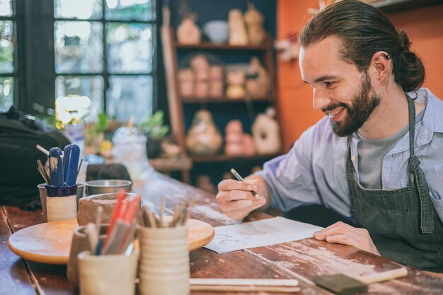 happy pottery artist designer enjoy sketch design handmade clay mug cup work small business workshop