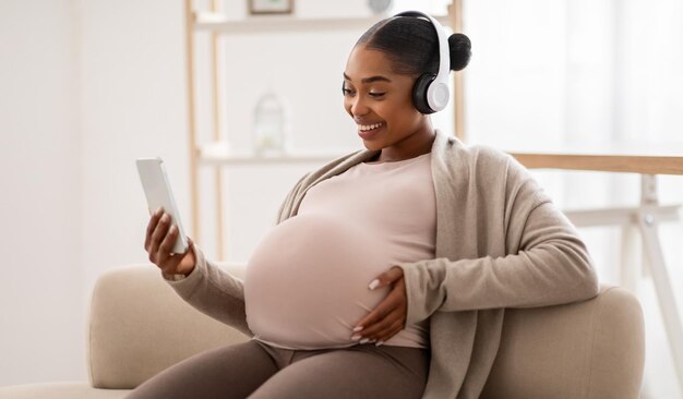 Photo happy pregnant black woman listening to music