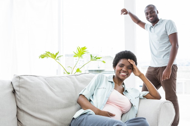 Happy pregnant couple in living room at home