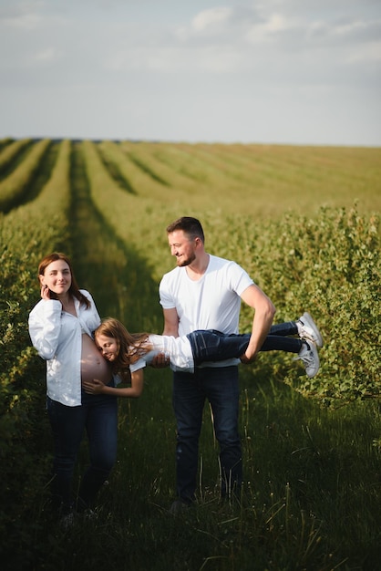 Happy pregnant couple with daughter in summer nature