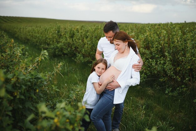 Happy pregnant couple with daughter in summer nature