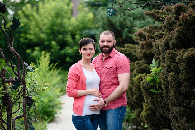 Happy pregnant family talking a walk in the park