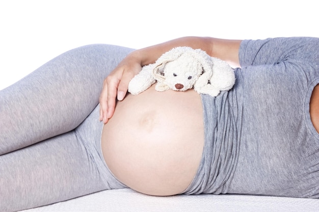 Счастливая беременная девушка лежит на белом фоне