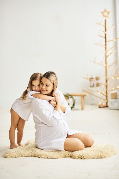 Happy pregnant mother and her daughters hug each other