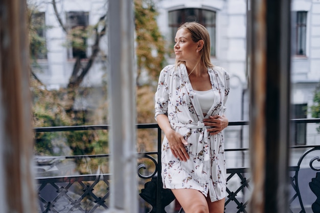 Happy pregnant woman in bathrobe hugging belly on terrace