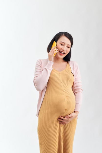 Happy pregnant woman calling on smartphone at home