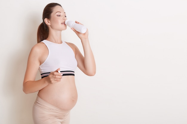 Happy pregnant woman drinking yogurt from bottle