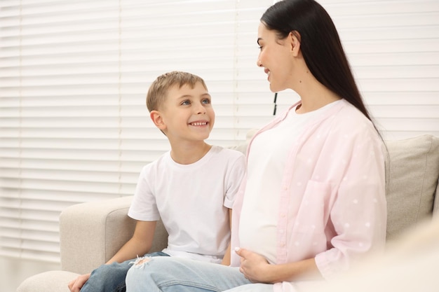 happy pregnant woman spending time with her son at home