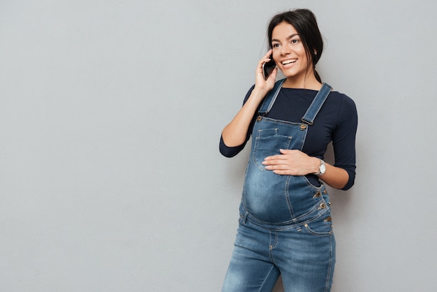 Happy pregnant woman talking by mobile phone