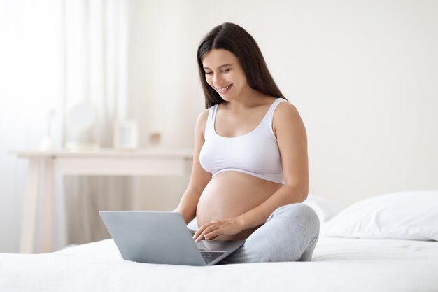 Happy pregnant woman using computer at home