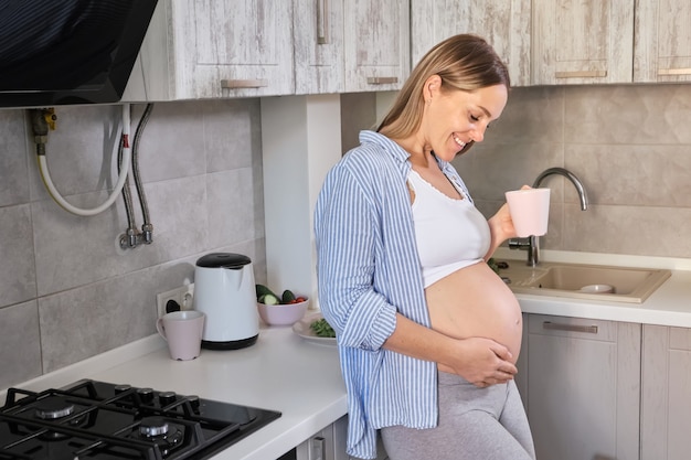 Happy pregnant woman with cup of tea