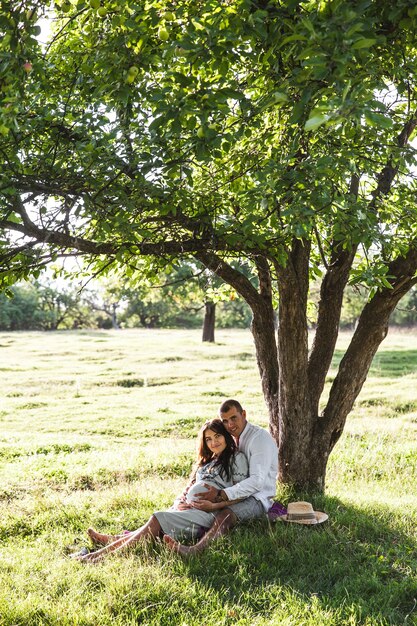 Happy pregnant woman with her husband at sunset