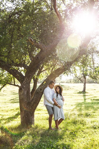 Happy pregnant woman with her husband at sunset