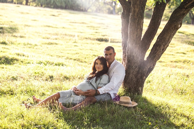 Happy pregnant woman with her husband at sunset