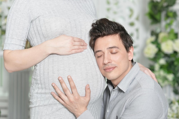 自宅で夫と幸せな妊娠中の女性妻の腹に頭を持つ男