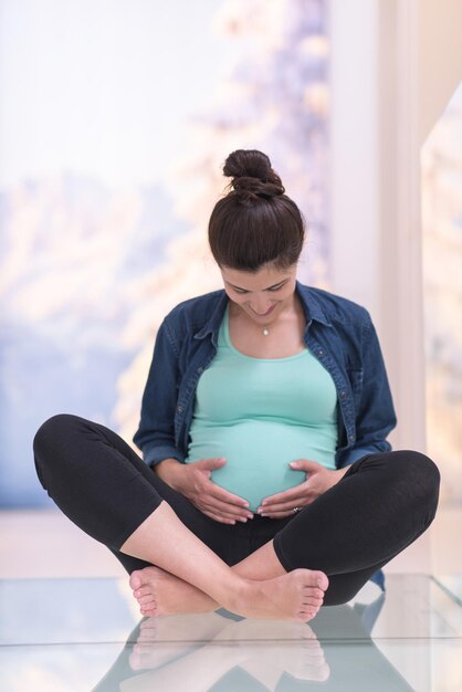 happy pregnant women enjoying pregnancy relaxing at home sitting on the floor