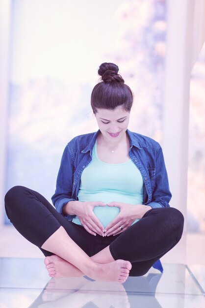 幸せな妊婦が妊娠を楽しんで 家で床に座ってリラックスしています