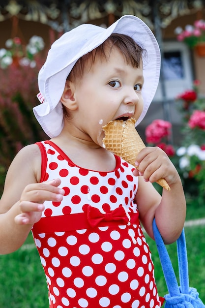 写真 晴れた夏の日にワッフルコーンでカラフルなアイスクリームを食べている幸せな幼稚園の女の子