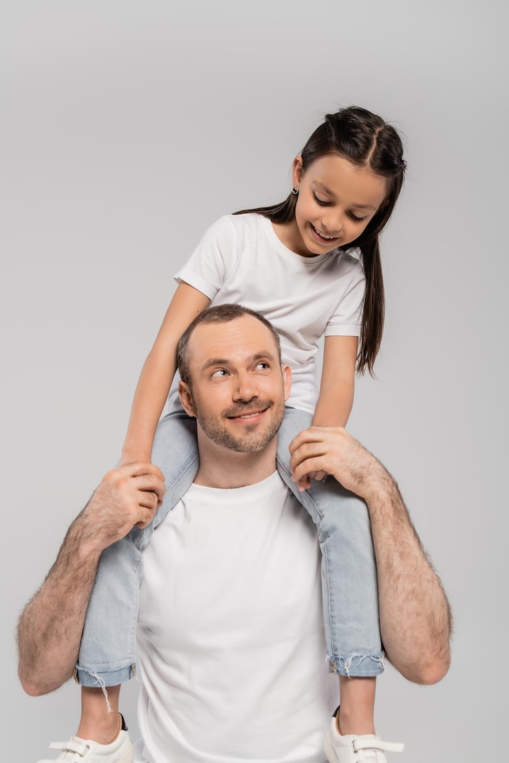Photo happy preteen daughter with long brunette hair sitting on shoulders of unshaved and cheerful father