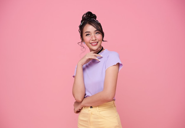 Happy pretty Asian teenage girl isolated on pink background.