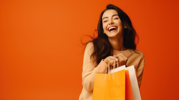 Счастливая красивая девушка в модной одежде с бумажным пакетом на оранжевом фоне