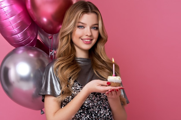 Happy pretty girl with cream cake and pink balloons