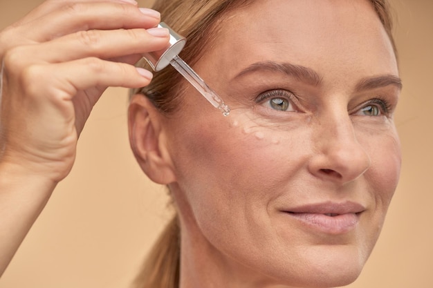 Happy pretty lady applying an antiaging sash under the eyes