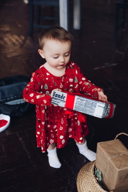 Bambina graziosa felice in regali rossi di natale di apertura del vestito da pigiama.