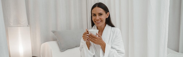 スパ サロンでコーヒーを飲みながら休憩しながら楽しんで幸せなきれいな女性