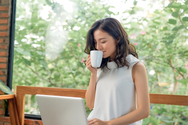 ソファに座ってラップトップを使用して幸せなきれいな女性