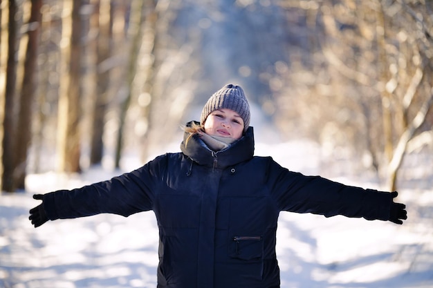 写真 晴れた日に冬の森で腕を横に広げた幸せな美しい女性