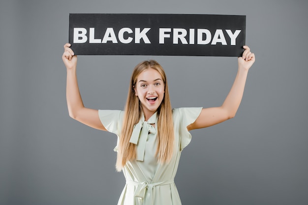 Happy pretty woman with black friday sign isolated over grey