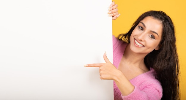 Photo happy pretty young caucasian brunette woman point finger at banner with blank space for words