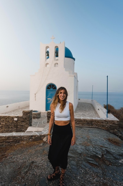 シフノス島の典型的なギリシャの教会の隣で夏休みを過ごす幸せなかなり若い女の子