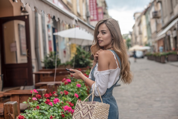 Happy pretty young teenager girl holding bags keeping a conversation with the mobile phone