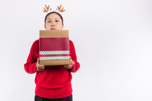 Happy pretty young woman holding gift box over gray background