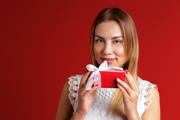 Happy pretty young woman holding gift box