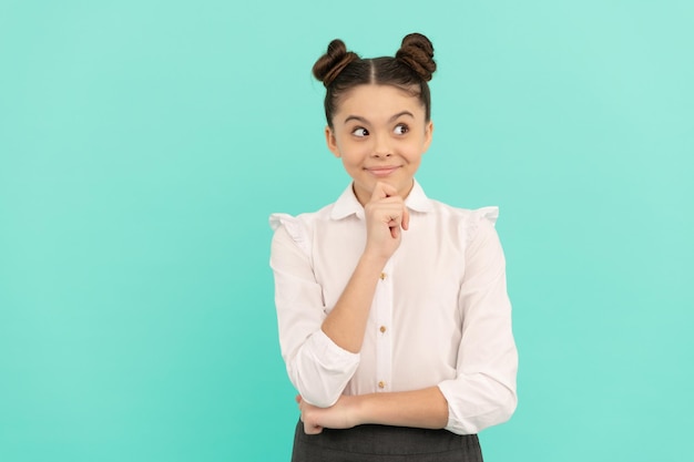 Happy primary school kid think looking away blue background thinking