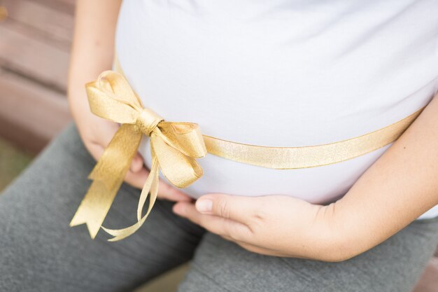 Happy and proud pregnant woman holding  her belly in a park 