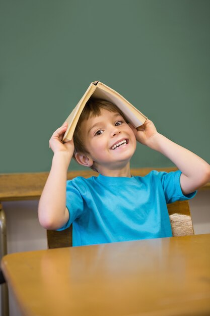 책상에 그의 머리에 책을 들고 행복 한 학생